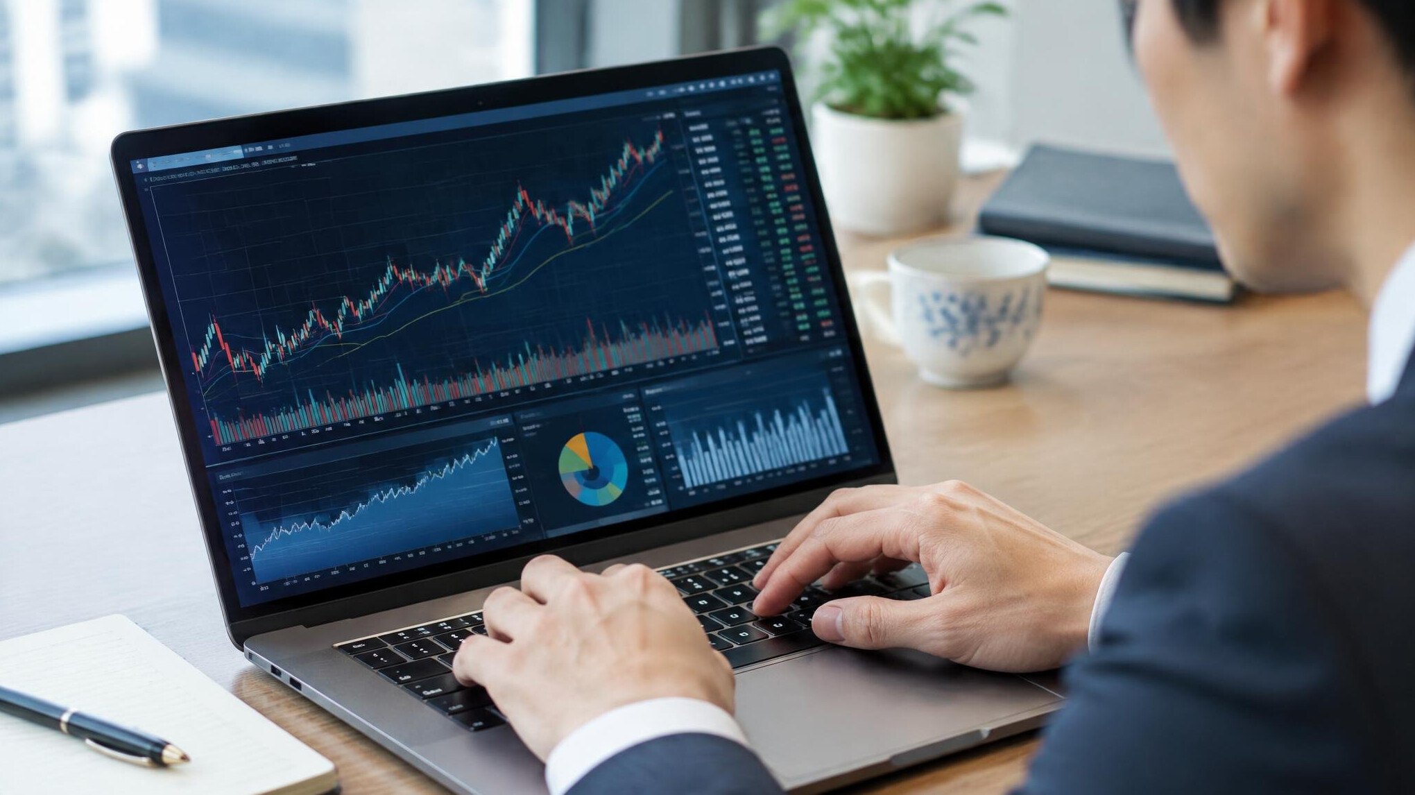 Close-up of hands typing on a laptop showing financial charts